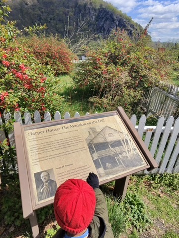 A child reading the Harper House historical marker